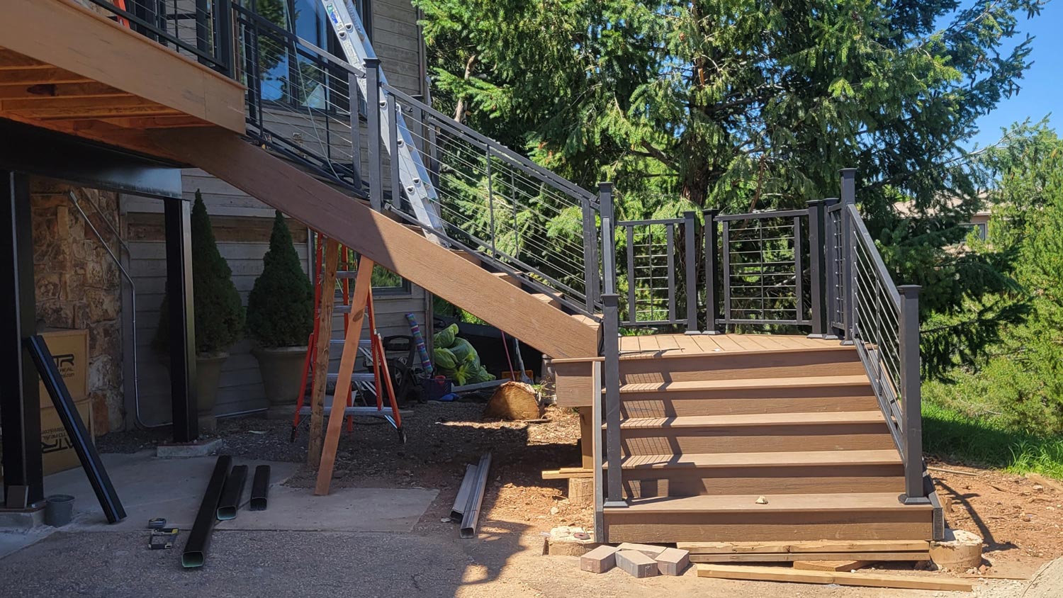 Composite Deck & Metal Railing Composite deck stairs with black metal balusters and a wood top rail