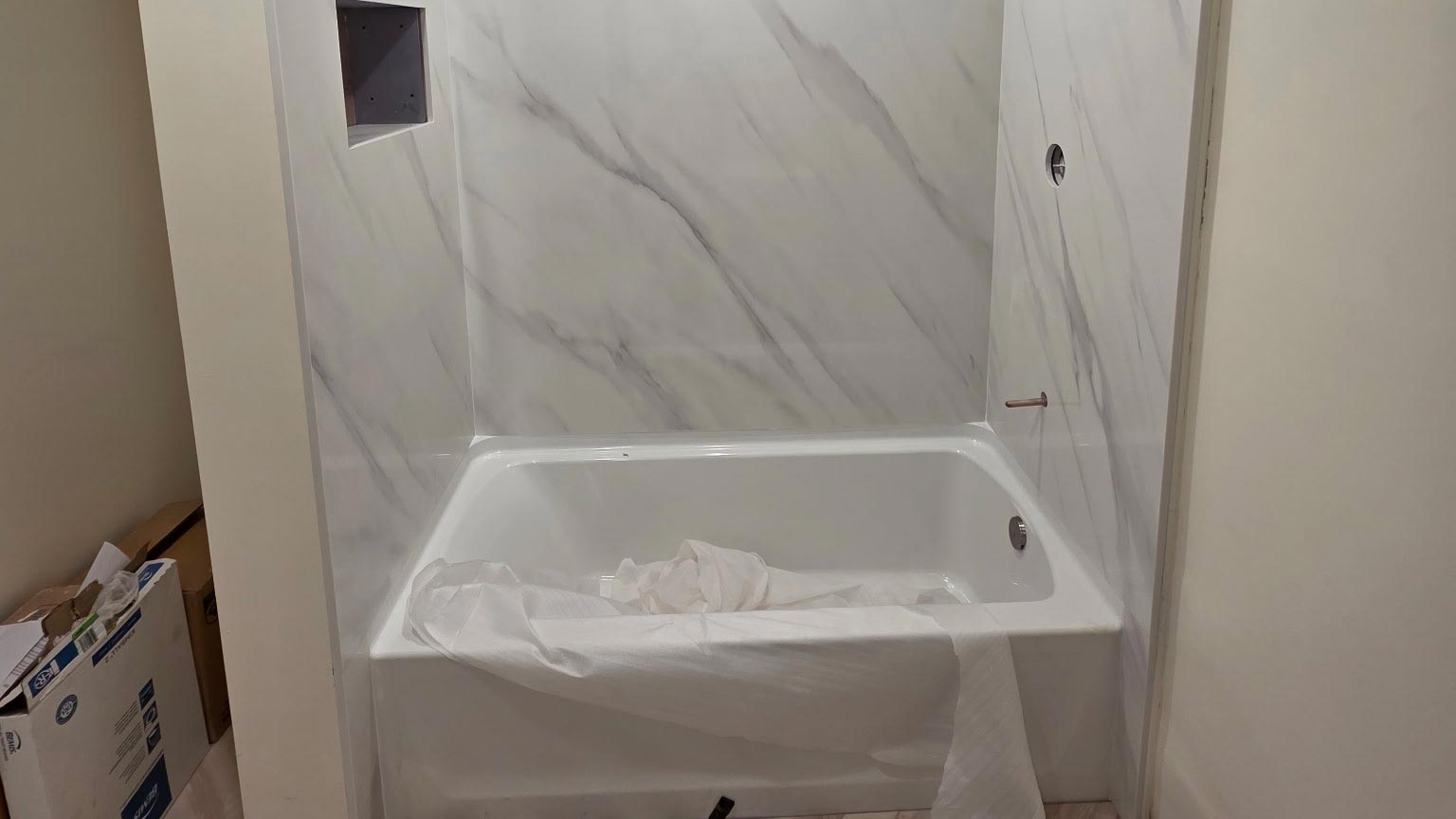 Tub-to-Shower Conversion Tub-to-shower conversion in progress with marble-look wall panels installed in the alcove