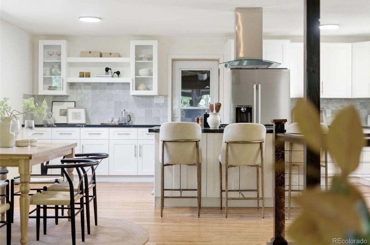 White Island & Range Hood White kitchen island facing a custom range hood, with the dining area beyond